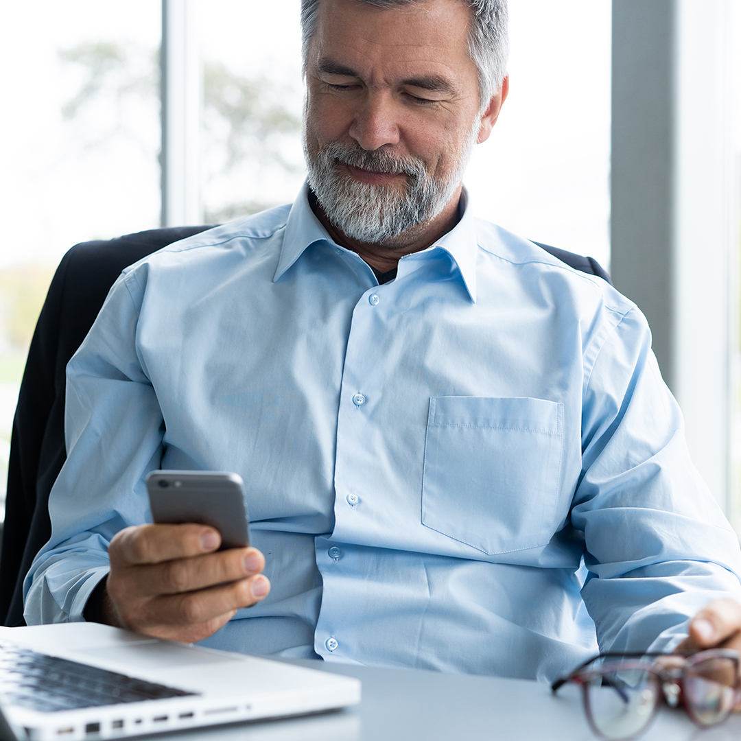 Smiling business man looking at his mobile phone