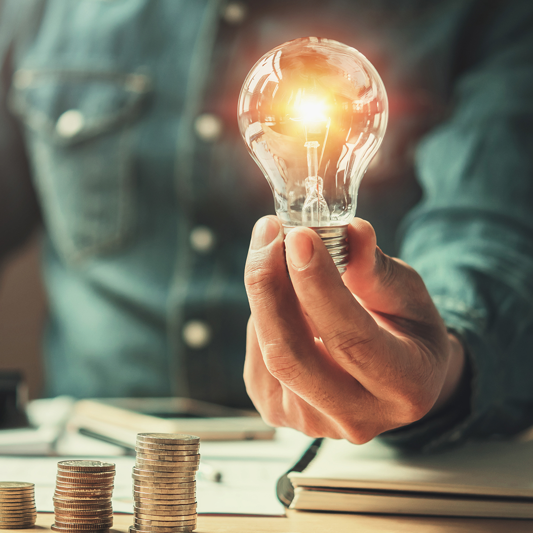 Man holding a light bulb next to some change